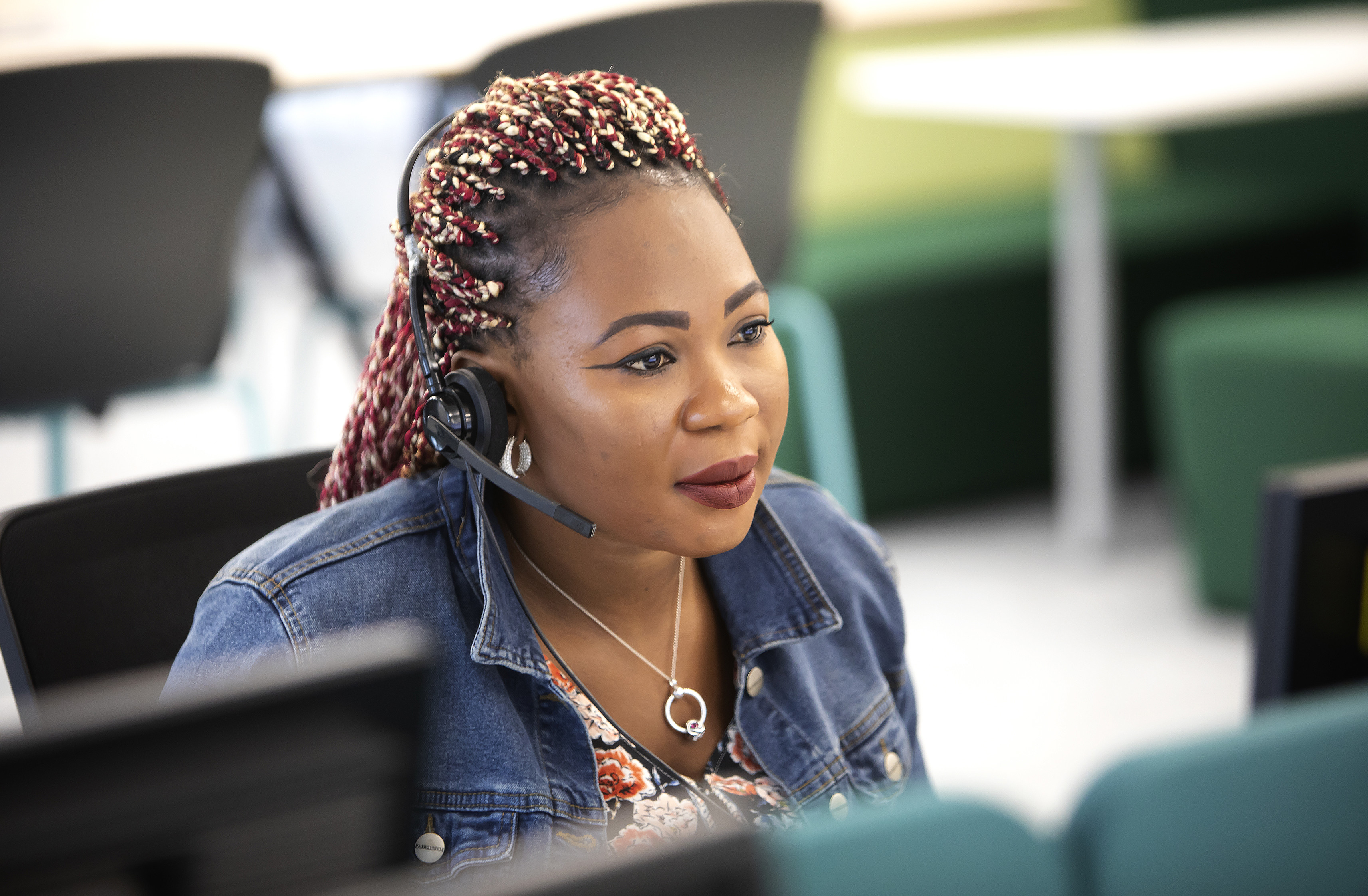 A woman is wearing a headset and looking at a computer screen.