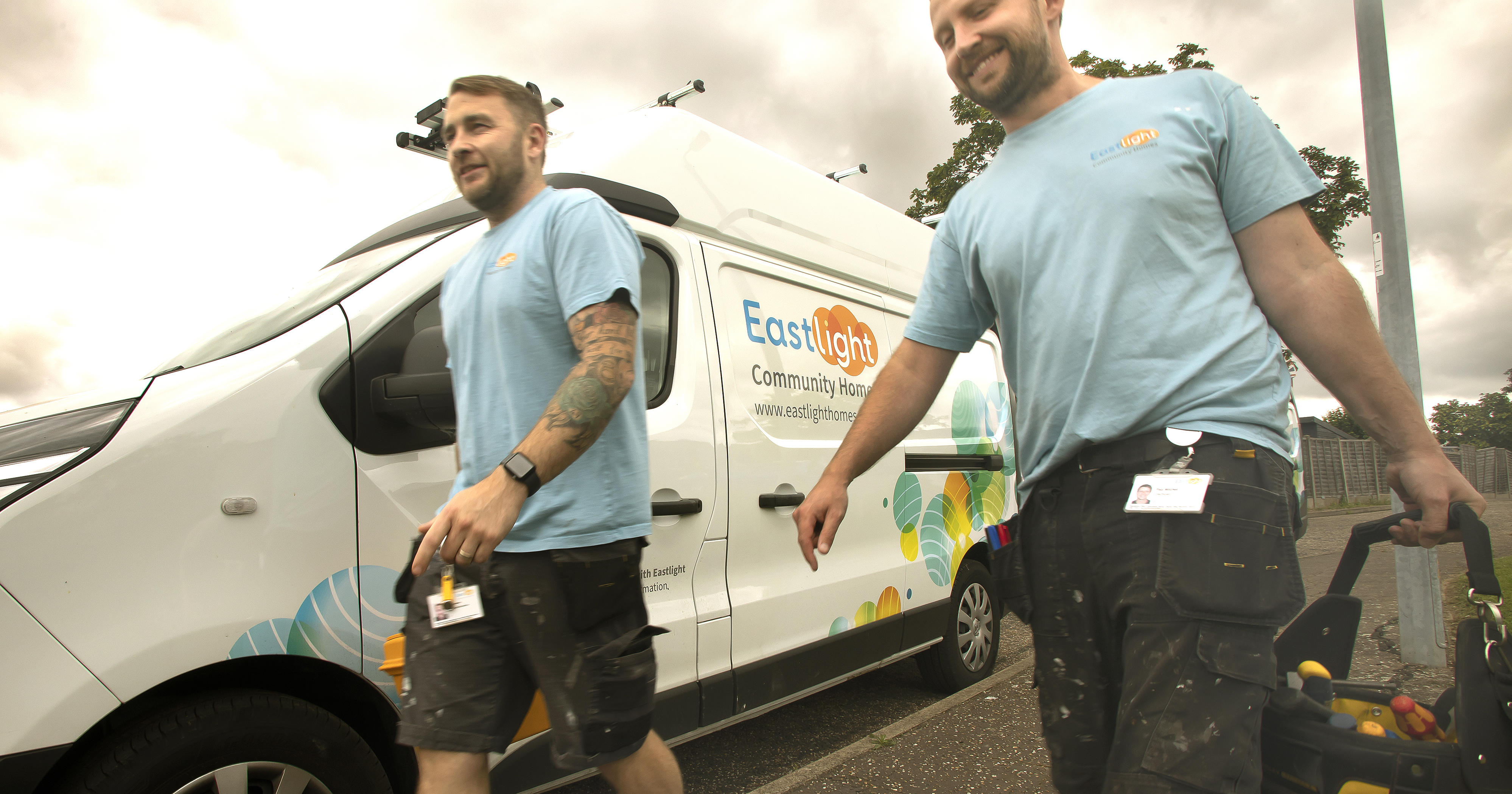 Two Eastlight tradesmen wearing Eastlight tshirts are walking beside an Easlight white van.