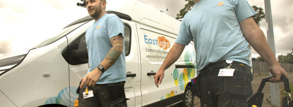 Two Eastlight tradesmen wearing Eastlight tshirts are walking beside an Easlight white van.