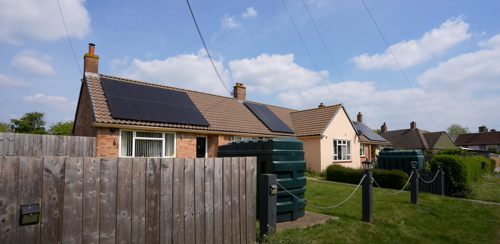 A row of bungalows with solar panels on their roofs.
