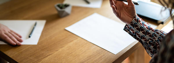 Three people are sat at a desk. You can see their hands above the desk.