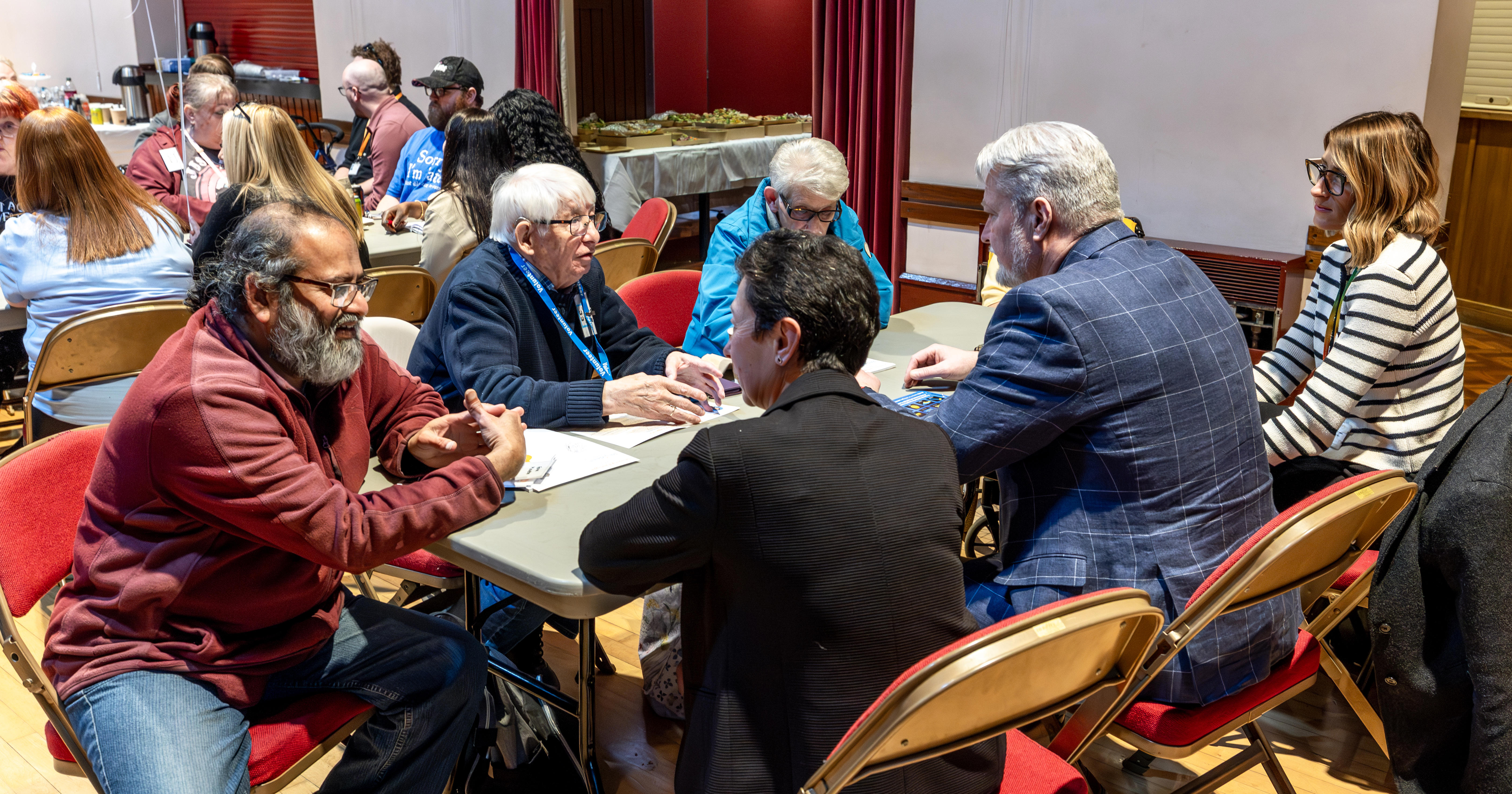A group of residents and Eastlight colleagues are sat around a table. They are all talking.