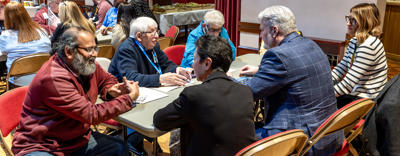 A group of residents and Eastlight colleagues are sat around a table. They are all talking.