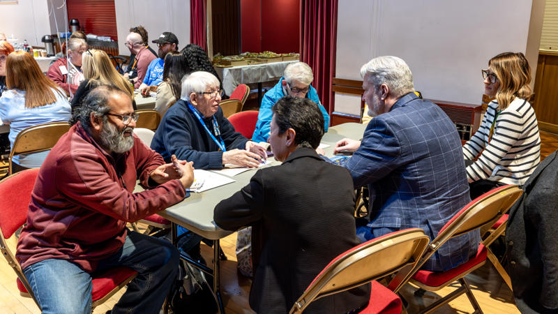 A group of residents and Eastlight colleagues are sat around a table. They are all talking.
