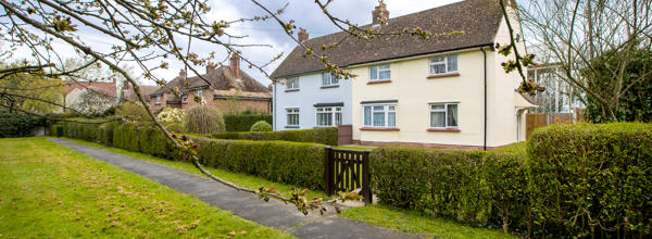 Two houses with a hedges around them and entrance gates.