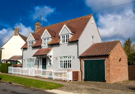 A house with white fencing around it and a garage attached.