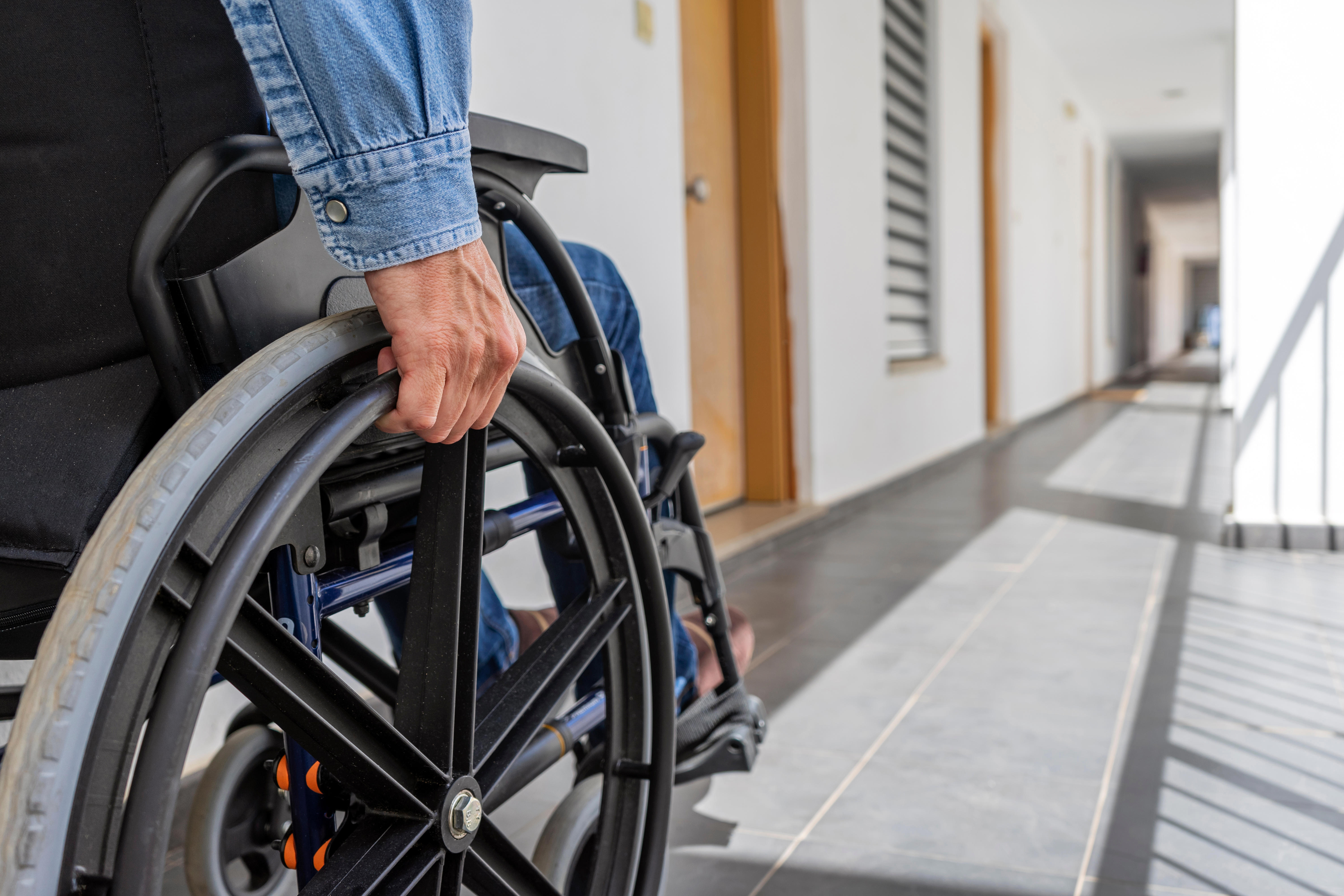 A person is holding onto the wheels of their wheelchair.