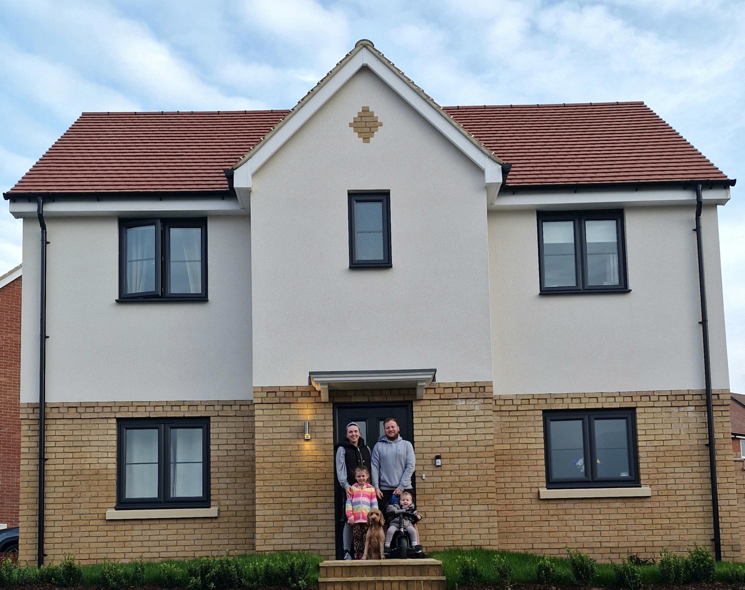 Charlea Norris, her partner and their children and dog are stood in front of their front door.