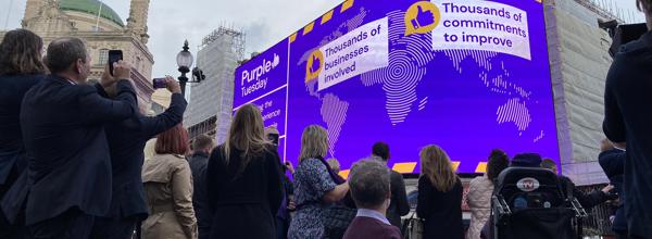 Purple and partners, including Eastlight CEO Emma Palmer, looking back on the lights at Piccadilly Circus, lit up in Purple Tuesday messaging