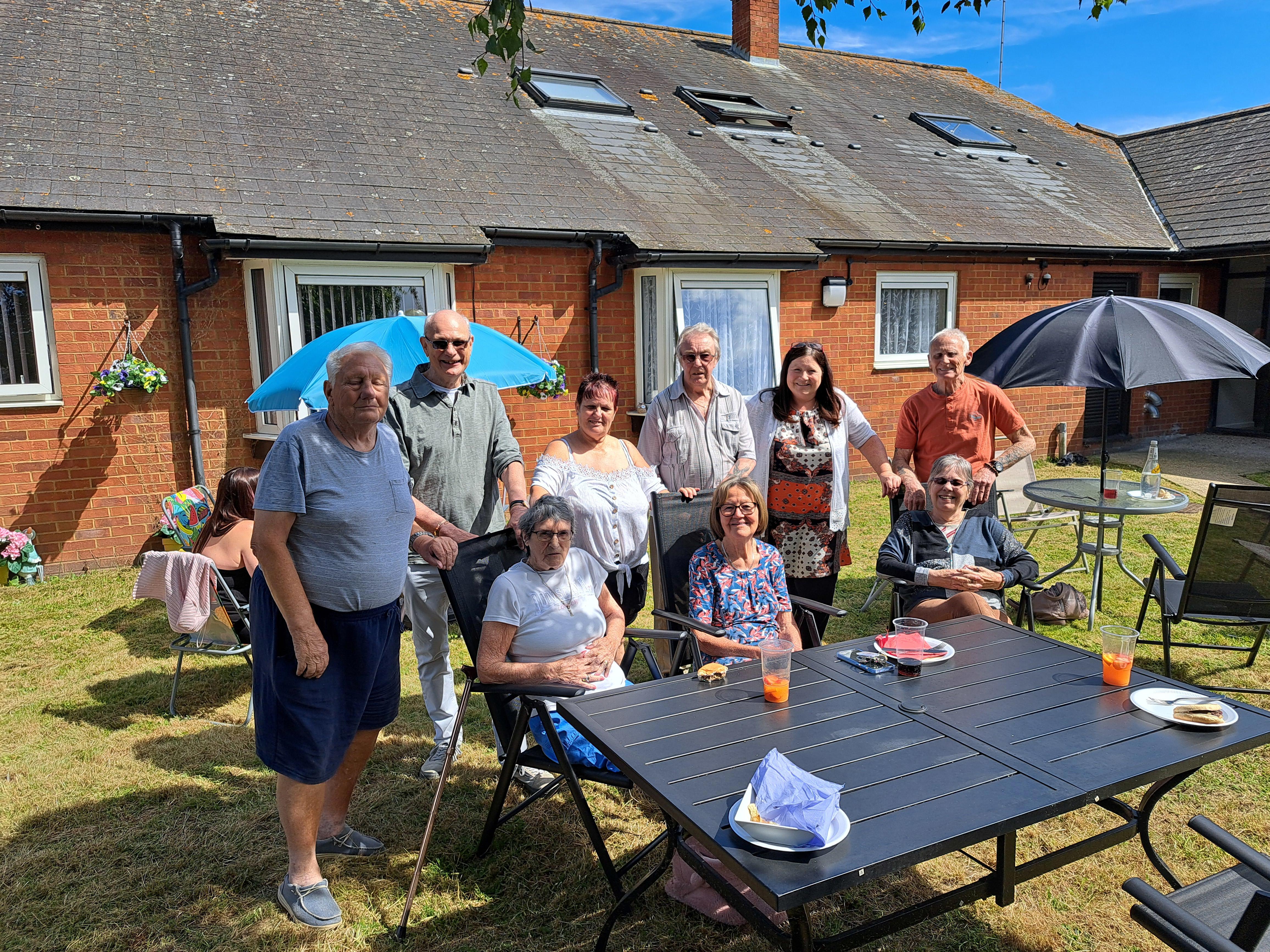 A group of residents are sat around a table at a BBQ.