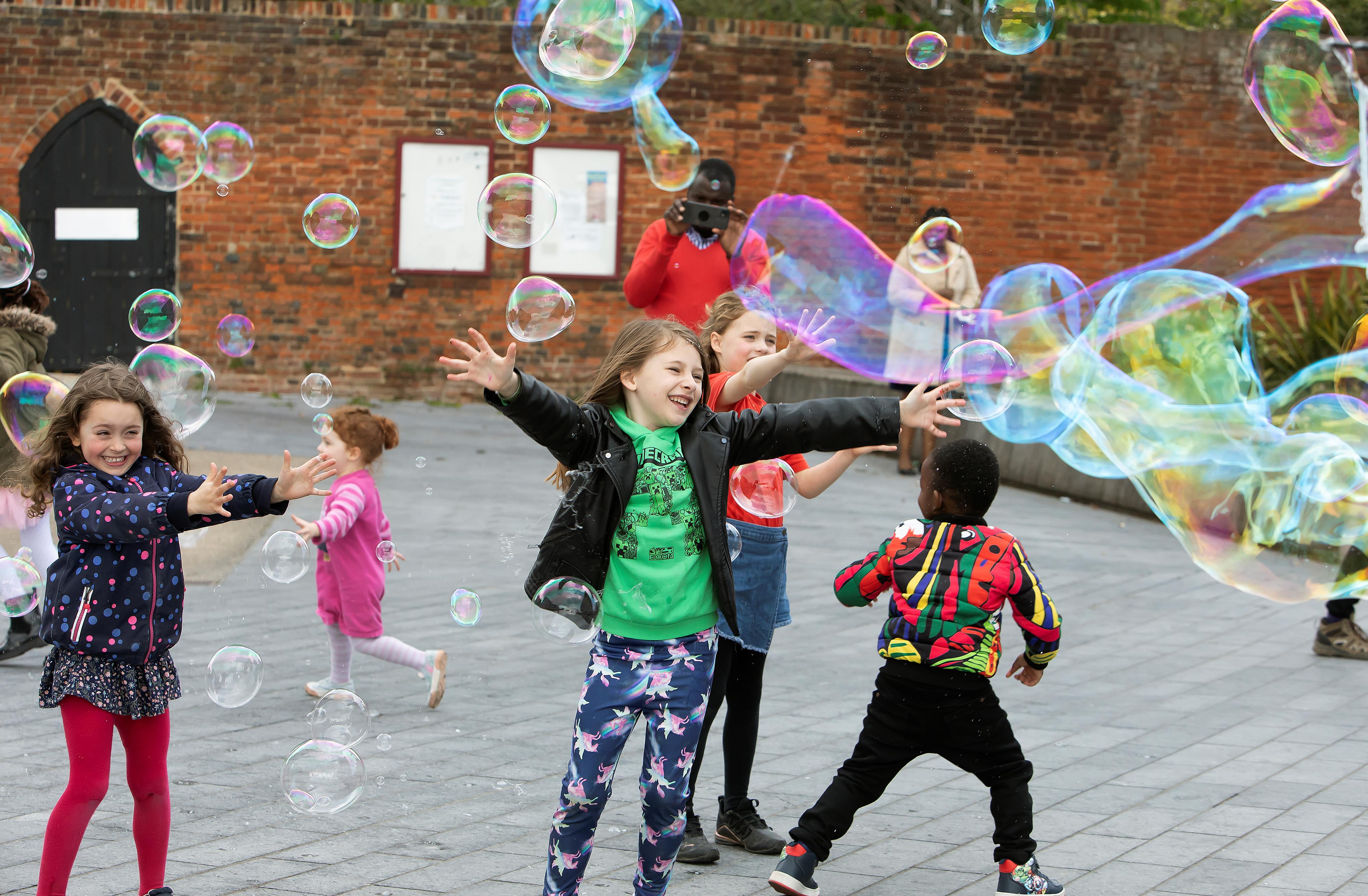 Children playing outside with large bubbles.
