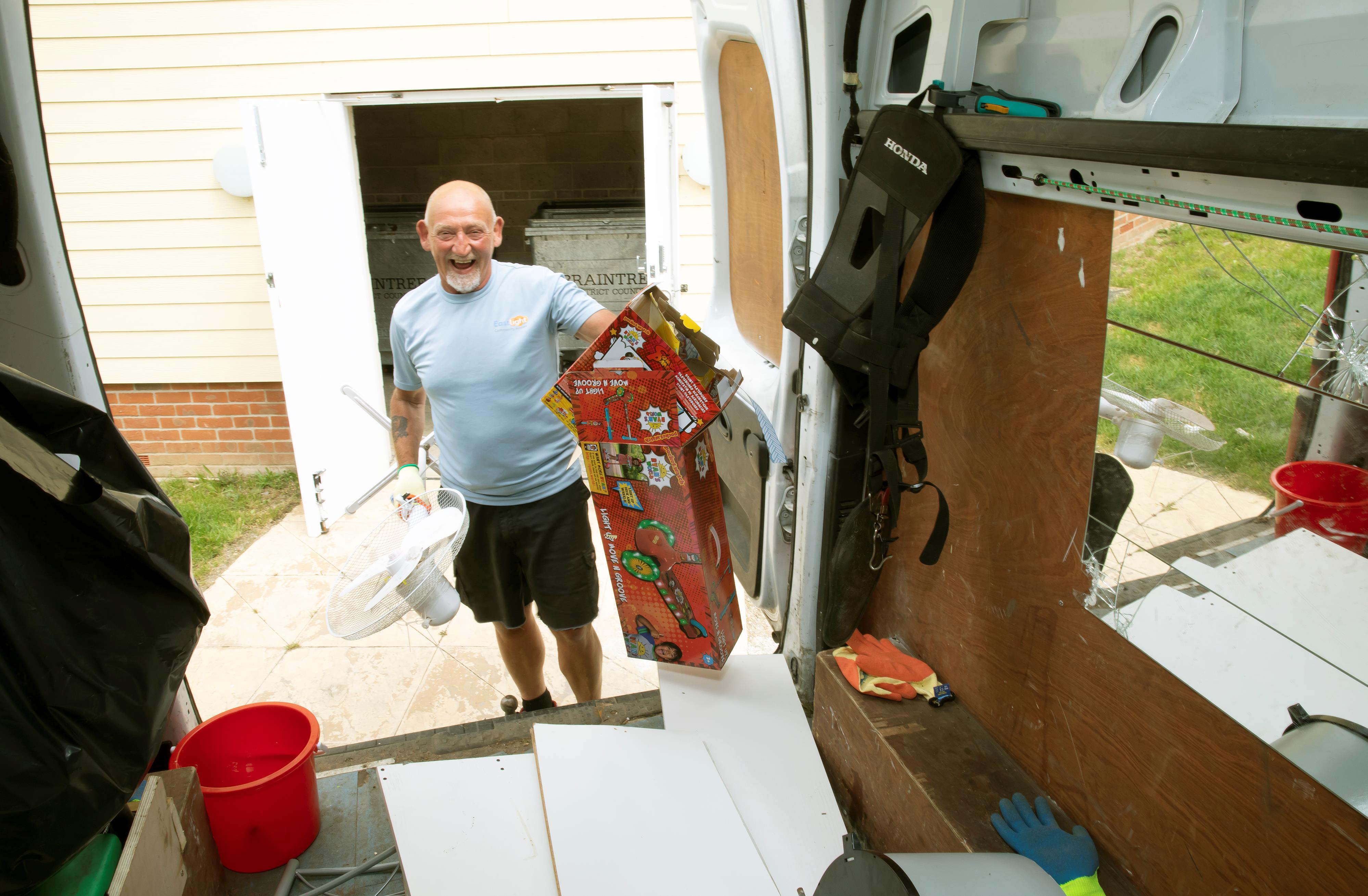 Estate Ranger, Marc Alliston, is putting unwanted items and cardboard into the back of his van. The point of view is from inside the van and he is smiling.